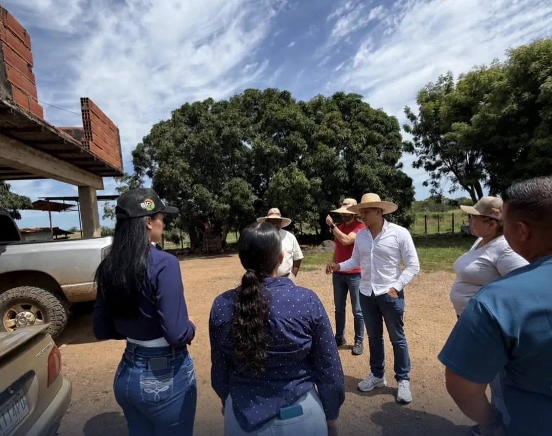 Un grupo conversa al aire libre junto a vehículos de una finca.