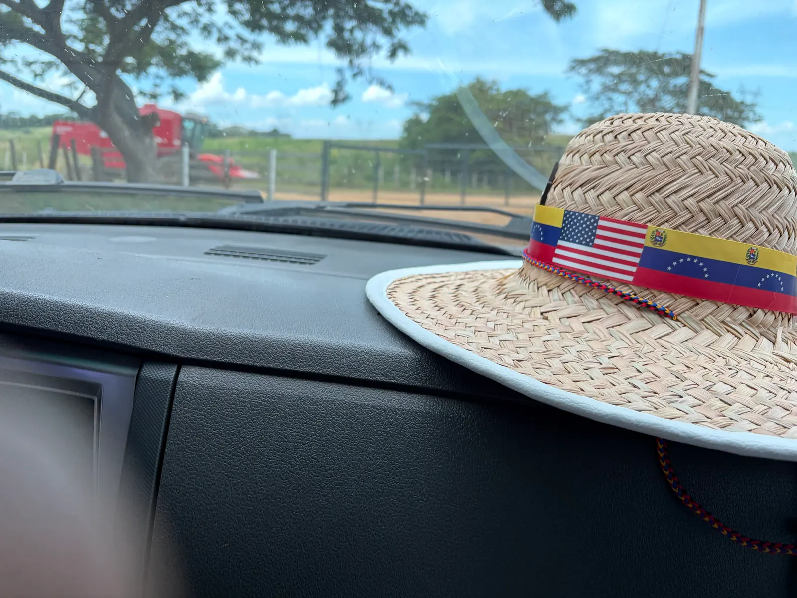 Un sombrero de paja con las banderas de Venezuela y Estados Unidos sobre el tablero de un vehículo.