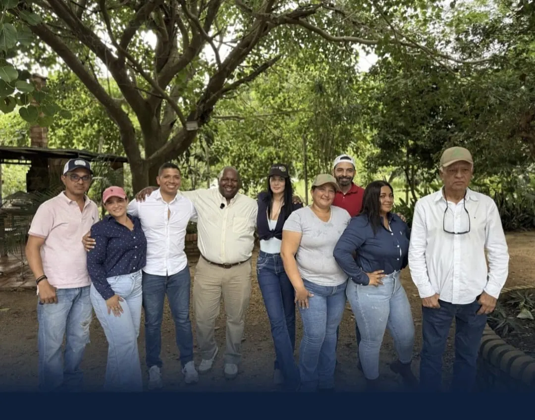 Integrantes de la delegación visitante y productores locales posan juntos bajo los árboles.
